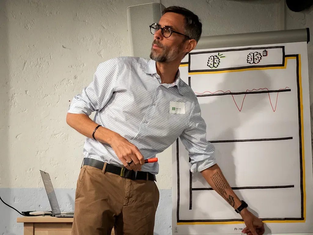Un animateur d’atelier montre une courbe d’émotions dessinée sur un tableau de papier.